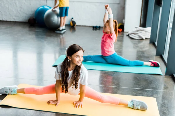 Bambini carini che fanno spago su stuoie fitness in palestra — Foto stock