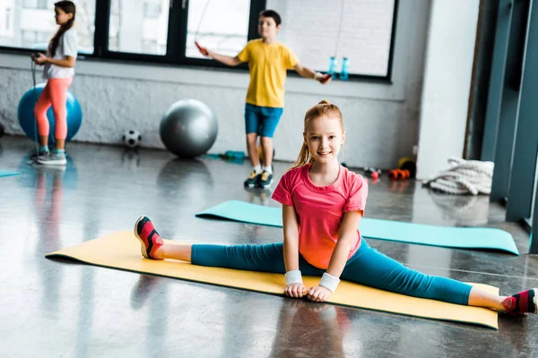 Excited kid doing twine on yellow fitness mat — Stock Photo