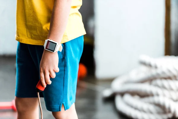 Vista parcial do menino em smartwatch segurando corda de salto — Fotografia de Stock