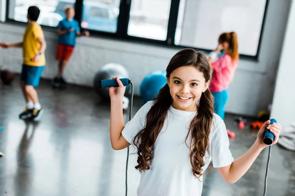 Enfant ludique posant dans la salle de gym avec corde à sauter — Photo de stock