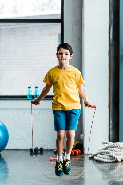 Brunette boy in yellow t-shirt jumping with skipping rope — Stock Photo