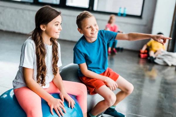 Niños preadolescentes charlando mientras están sentados en pelotas de fitness - foto de stock