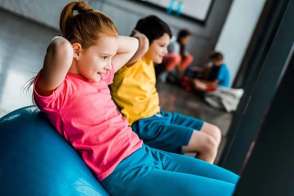 Crianças alegres fazendo exercícios abdominais com bolas de fitness — Fotografia de Stock