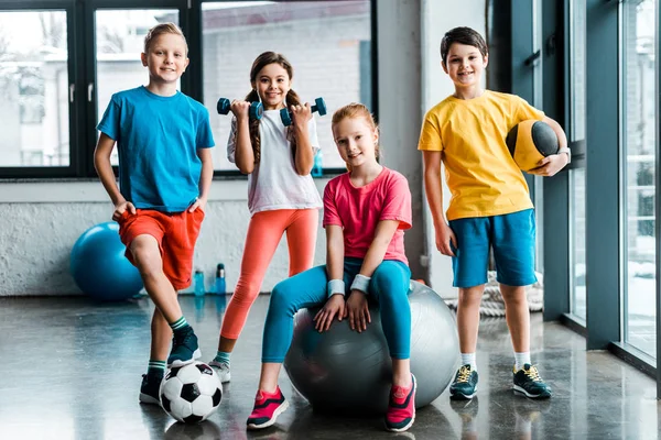Riendo niños preadolescentes posando con equipo deportivo - foto de stock