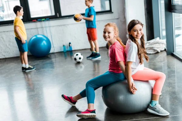 Rindo amigos pré-adolescentes sentados na bola de fitness — Fotografia de Stock