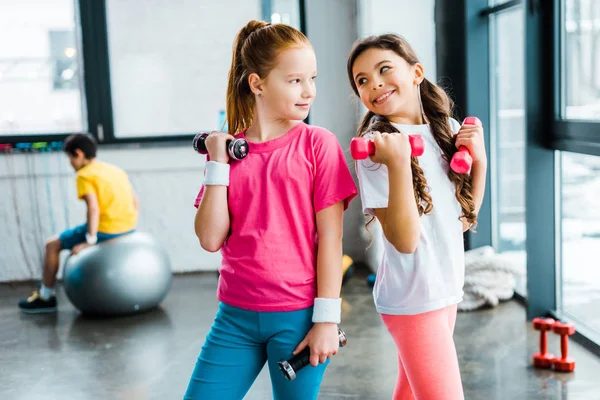 Kids looking at each other while posing with dumbbells — Stock Photo