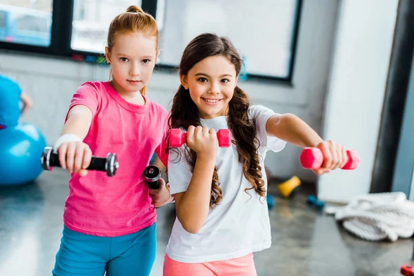 Niños activos haciendo ejercicio con pesas en el gimnasio - foto de stock