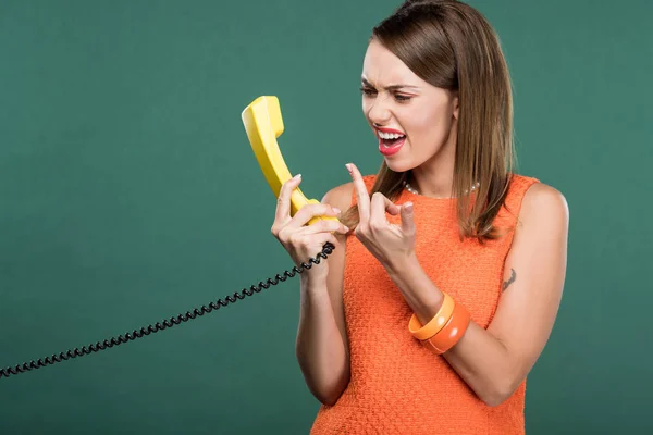 Bela mulher zangada gritando com telefone retro e mostrando dedo do meio isolado no verde — Fotografia de Stock