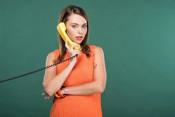 Schöne stilvolle Frau schaut in die Kamera und spricht auf Retro-Telefon isoliert auf Grün mit Kopierraum — Stockfoto