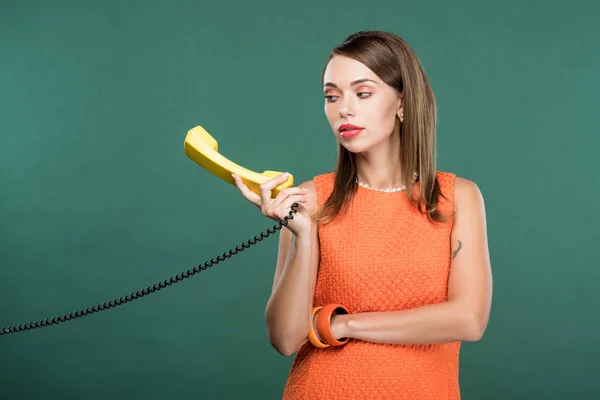 Hermosa mujer elegante sosteniendo teléfono retro aislado en verde - foto de stock