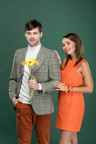 Hermosa mujer sonriente abrazando al hombre en ropa vintage con flores aisladas en verde - foto de stock