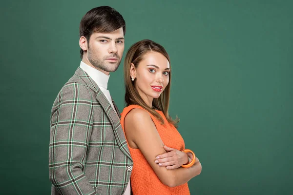 Красивая пара в винтажной одежде позирует и смотрит на камеру, изолированную на зеленый с копировальным пространством — стоковое фото