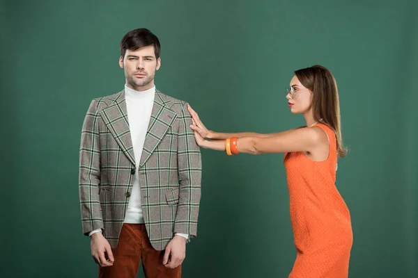 Bela mulher empurrando homem bonito em roupas vintage isolado no verde — Fotografia de Stock