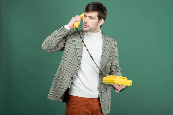 Hombre guapo en ropa vintage hablando en el teléfono de línea rotatoria retro aislado en verde - foto de stock