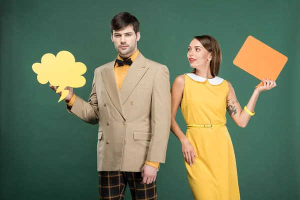 Belo casal em roupas vintage segurando bolha discurso e pensamento bolha isolado no verde — Fotografia de Stock