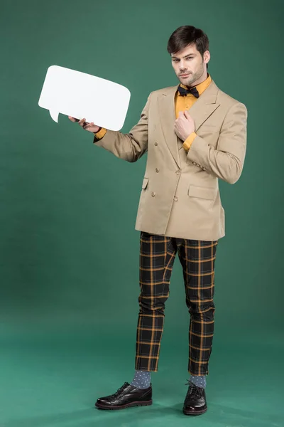 Handsome man in vintage clothes holding speech bubble on green background — Stock Photo