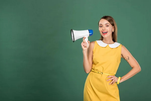 Belle femme élégante en robe jaune criant dans haut-parleur isolé sur vert avec espace de copie — Photo de stock