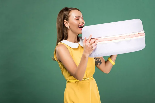 Красивая улыбающаяся женщина ест макарон модели изолированы на зеленый — стоковое фото