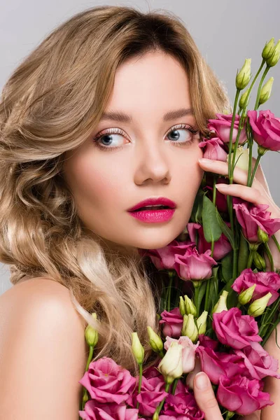 Mujer rubia hermosa desnuda posando con flores de Eustoma aisladas en gris - foto de stock