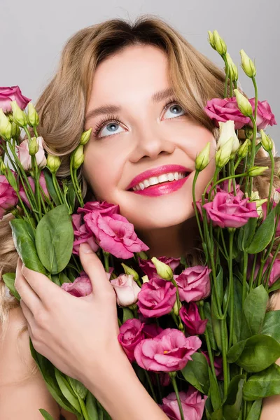 Nua primavera sorridente jovem segurando buquê de flores Eustoma isolado em cinza — Fotografia de Stock