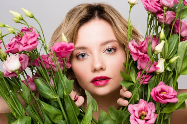 Bella primavera giovane donna guardando fuori dal bouquet di fiori di Eustoma isolati su grigio — Foto stock