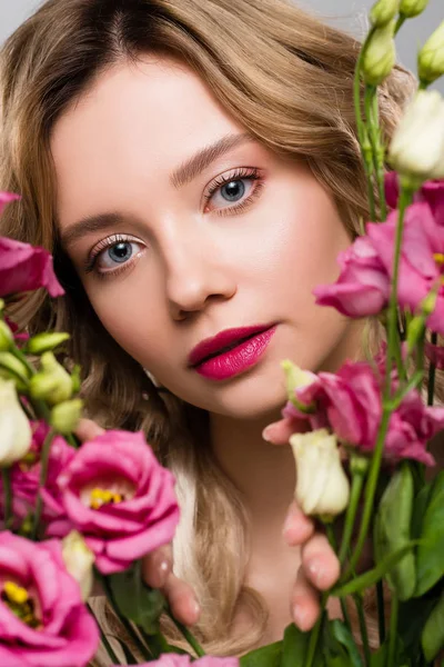 Nahaufnahme des Frühlings junge Frau schaut durch Eustoma-Blumen — Stockfoto