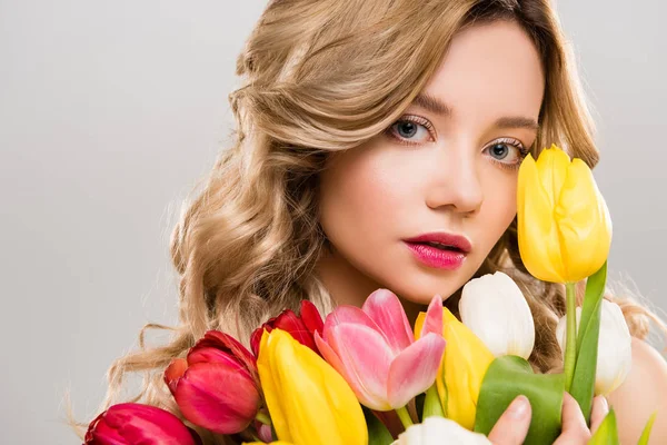 Young tender spring woman holding bouquet of colorful tulips isolated on grey — Stock Photo