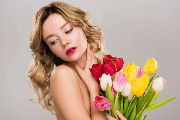 Desnuda joven atractiva mujer de primavera posando con ramo de tulipanes coloridos aislados en gris - foto de stock