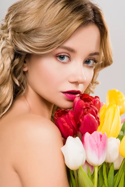 Молодая элегантная весенняя женщина с букетом разноцветных тюльпанов, изолированных на сером — стоковое фото