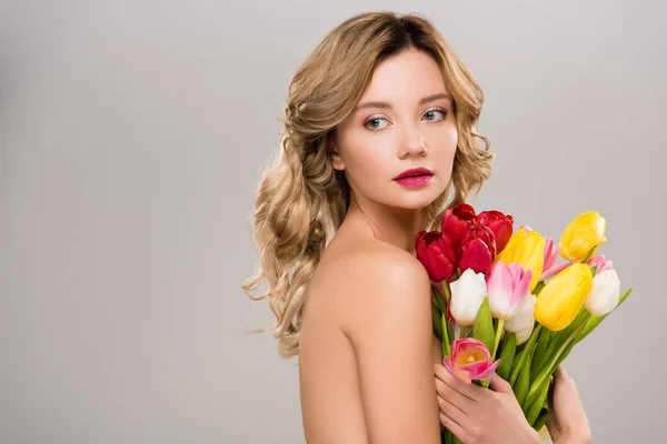 Joven mujer de primavera desnuda sosteniendo ramo de tulipanes de colores aislados en gris - foto de stock