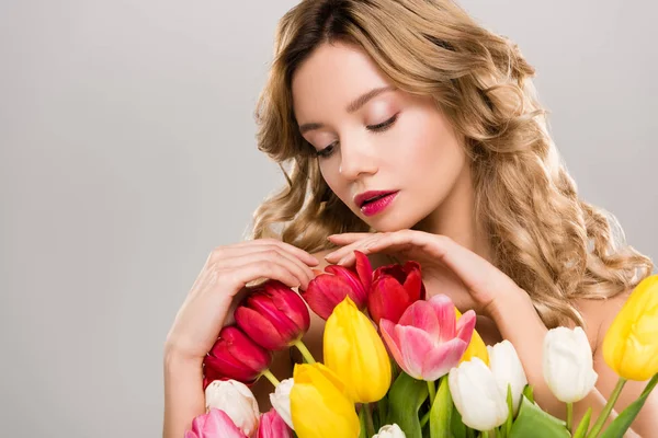 Jeune jolie printemps femme touchant bouquet de tulipes colorées isolées sur gris — Photo de stock