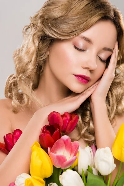 Молода оголена приваблива весняна жінка з закритими очима позує з букетом барвистих тюльпанів ізольовані на сірому — стокове фото