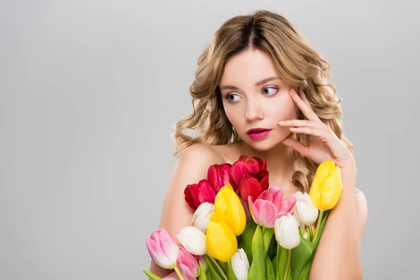Молода оголена весна жінка позує з тюльпанами ізольована на сірому — стокове фото