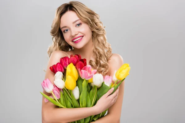 Young beautiful smiling naked spring woman holding bouquet of colorful tulips isolated on grey — Stock Photo