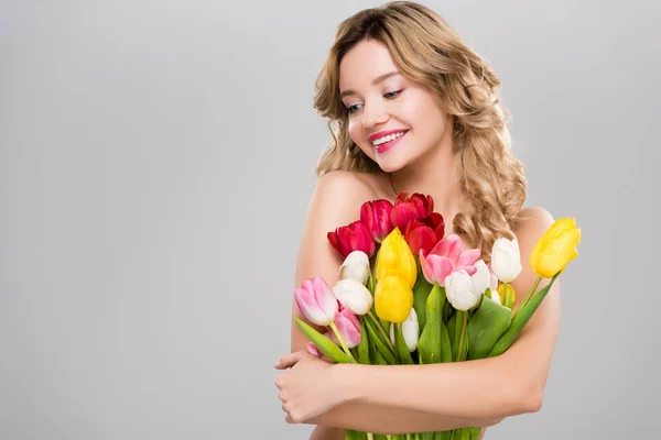 Молода красива усміхнена гола весняна жінка з букетом барвистих тюльпанів ізольована на сірому — стокове фото