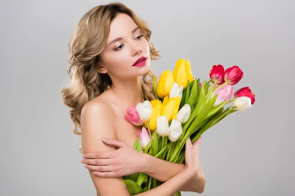 Young attractive spring woman holding bouquet of multicolored tulips isolated on grey — Stock Photo