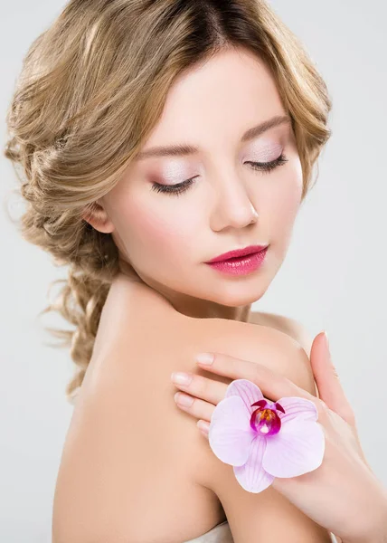 Hermosa tierna chica sosteniendo flor aislada en gris - foto de stock