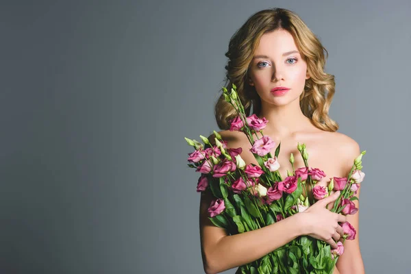 Nackte Frau mit Strauß Eustoma-Blumen isoliert auf grau — Stockfoto