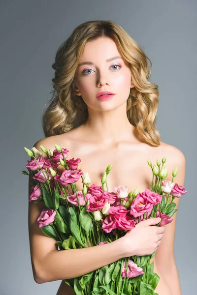Chica desnuda sosteniendo ramo de flores de eustoma aisladas en gris - foto de stock
