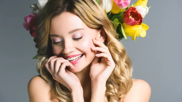 Cheerful girl with wreath of flowers on hair isolated on grey — Stock Photo