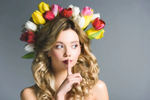 Chica con corona de flores en el pelo mostrando signo de silencio aislado en gris - foto de stock