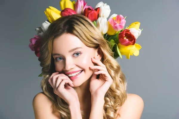 Усміхнена жінка з вінком квітів на волоссі ізольована на сірому — стокове фото
