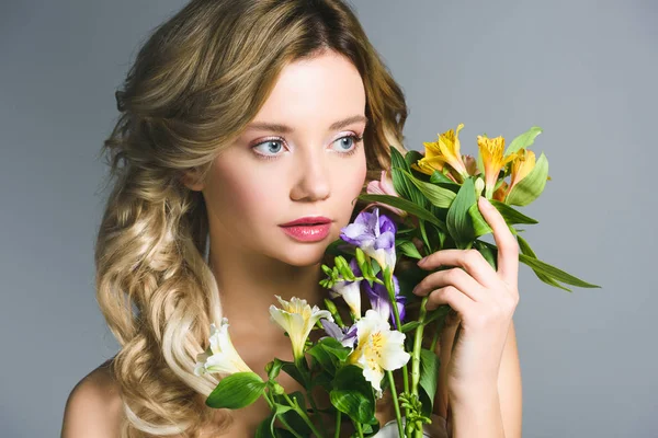 Attractive blonde young woman holding flowers in hand — Stock Photo