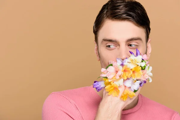 Homme couvrant la bouche de fleurs isolées sur beige — Photo de stock