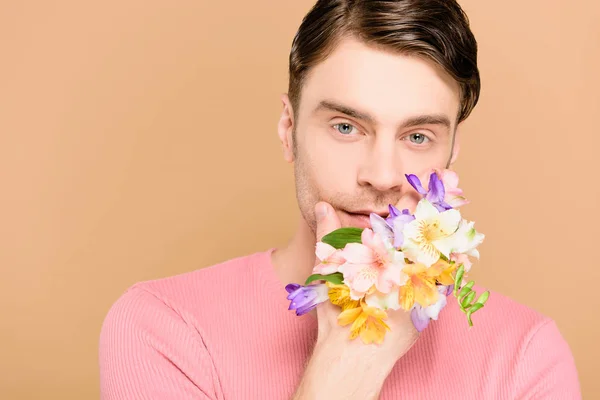 Homme couvrant le visage de fleurs à la main isolé sur beige — Photo de stock