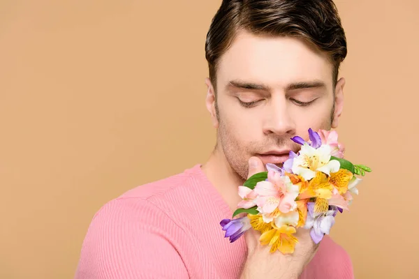 Schöner Mann mit zarten Alstroemeria-Blüten an der Hand isoliert auf beige — Stockfoto