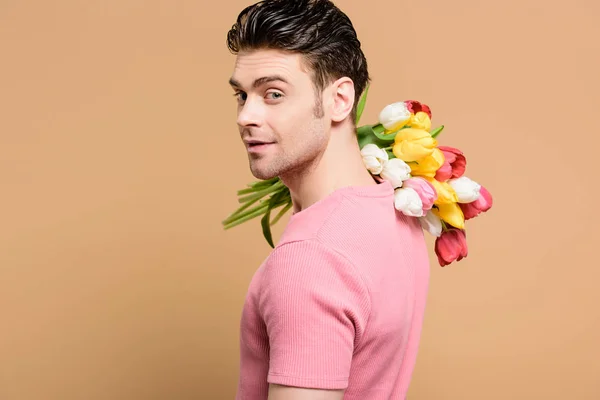 Homem feliz segurando buquê de flores no ombro isolado no bege — Fotografia de Stock