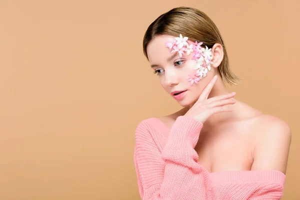 Ragazza pensosa con fiori sul viso isolato su beige — Foto stock