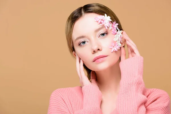 Elegant girl with flowers on face looking at camera isolated on beige — Stock Photo