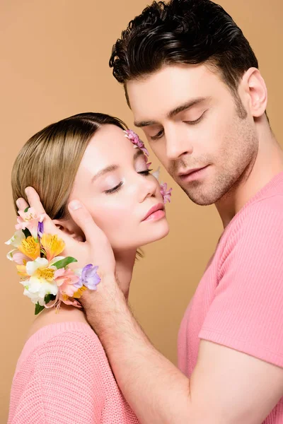 Tenero fidanzato con fiori di alstroemeria a portata di mano toccando il viso di attraente ragazza isolata sul beige — Foto stock